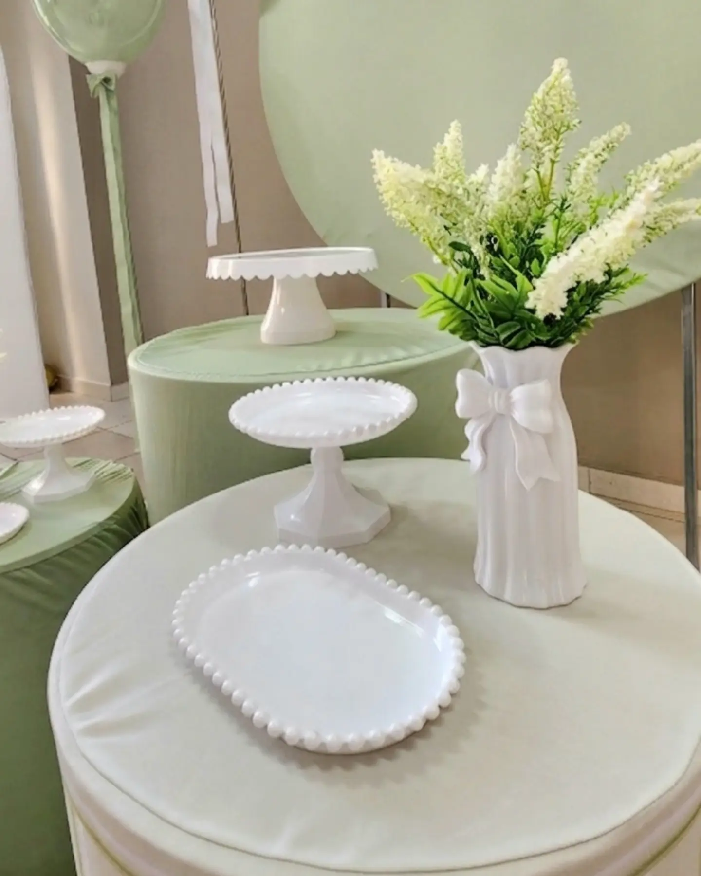 Mesa do Kit Encanto verde, com cake stand e vaso de flores brancas