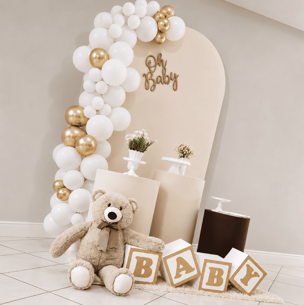 Decoração de chá de bebê em tons marrom e dourado, com arco de balões, ursinho e cubos BABY